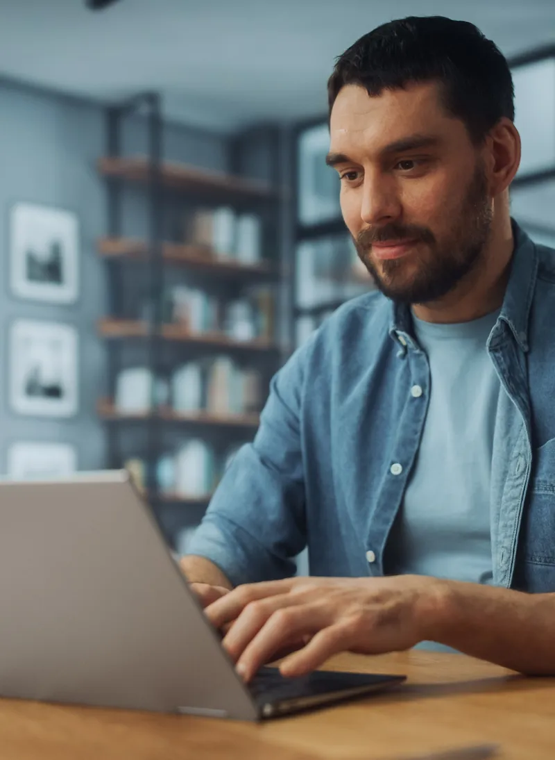 Un homme souriant travaillant sur sont ordinateur portable